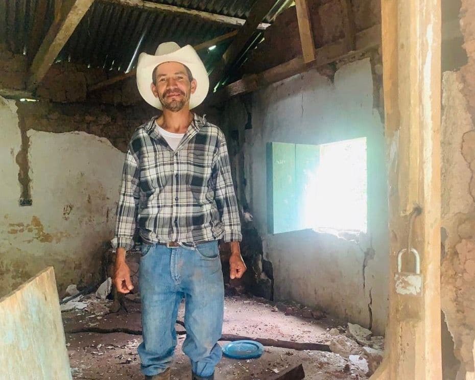 Moisés García in front of his destroyed family home